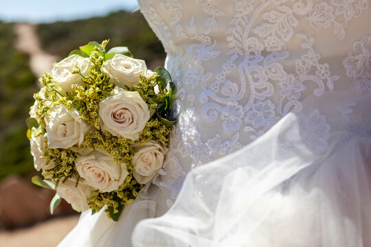 wedding bouquet of flowers and detail of a wedding gown
