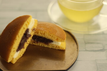 金塗り半月菓子皿に盛られたカットされたどら焼きと緑茶