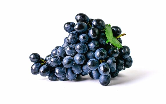 Black grapes, sweet fruit, water droplets with green grape leaves close-up, white background