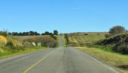 ruta en un camino montañoso, con cortes en la linea de vision por las subidas y bajadas, con cielo...