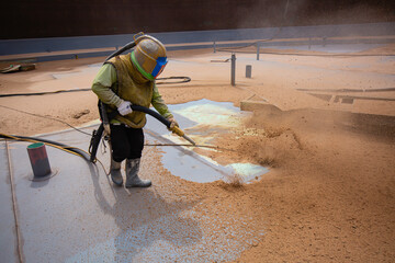 Male worker surface corrosion plate preparation by sandblasting bounce off of tank top deck.