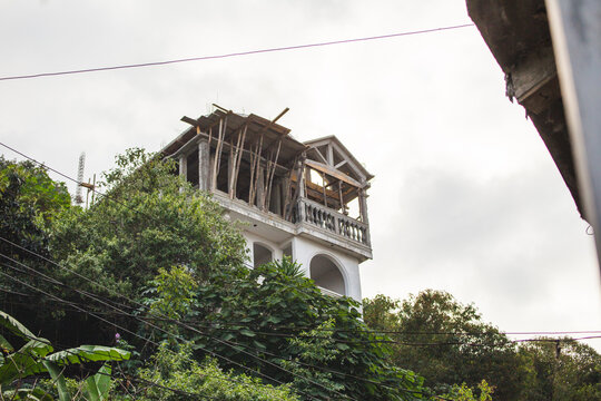 Old white house above forest of trees, abandoned building on Lake Atitlan in Guatemala