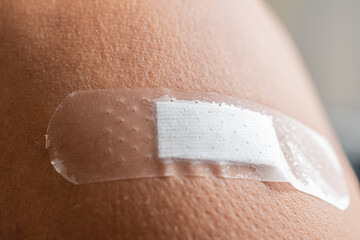 Medical adhesive plaster to stick wound on shoulder, arm close-up, wound healing guidelines