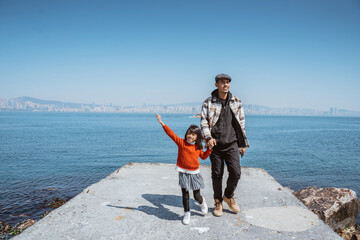 father and daughter walking together on the jetty next to marmara sea in clear blue sky