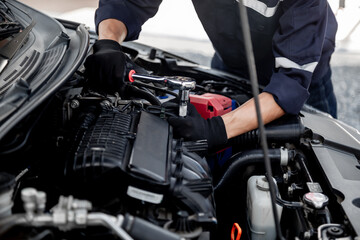 Naklejka na ściany i meble Car care maintenance and servicing, Close-up hand technician auto mechanic using the wrench to repairing change spare part car engine problem and insurance service support.