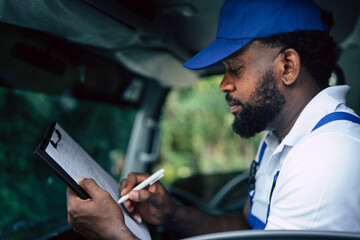 Portrait of courier black man working with checklist clipping board in the truck, Authentic worker with delivery occupation.