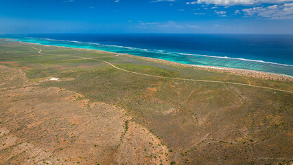 Areal view of the coastline in Cape Range National Park. The turquoise waters meeting the dry yet green bushland next to the rugged ridges of the range.