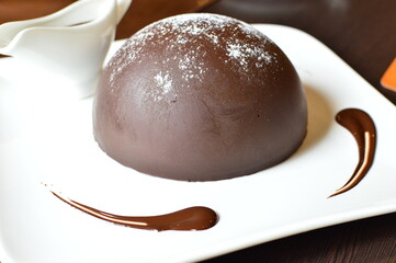Chocolate ball with ice cream inside on a white dish.