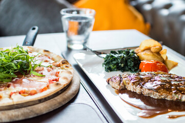 Thin Crust Pizza with bacon and meat steak with tomato sauce on the table.