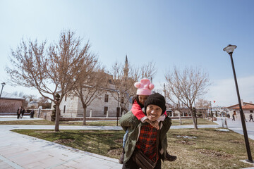 Obraz premium father carrying her daughter on his shoulder piggyback ride while visiting mosque in the city of konya turkey