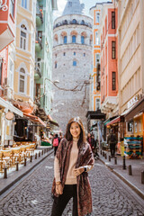woman walking through an alley full with cafe and historical building in istanbul turkey