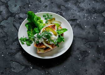 Delicious snack - fried haloumi and tartare sauce sandwich on a dark background, top view