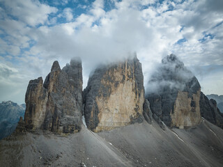 Cloudy day after the storm in the Dolomites mountains with mountain peaks looking up from the fog, mist, and clouds. 