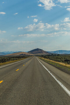 Empty western highway. Long road through high desert with mountain views.