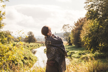 Woman cuddles into scarf in scenic outdoor landscape