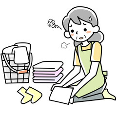 疲れた表情で洗濯物をたたむシニア女性