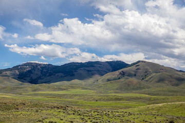 Obraz premium Green vally below mountain shaded by clouds