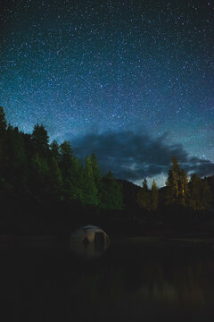 Star filled night sky with clouds, forest, tent,
