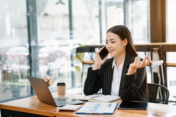  Asian business woman have the joy of talking on the smartphone, tablet and laptopon the modern office