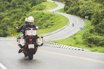 A man and a woman ride together on a sports motorcycle. Motorcyclists travel around the city during the day on a touring bike.