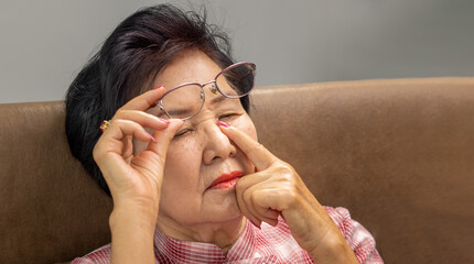 Asian senior older woman taking off glasses, suffering from dry eyes syndrome