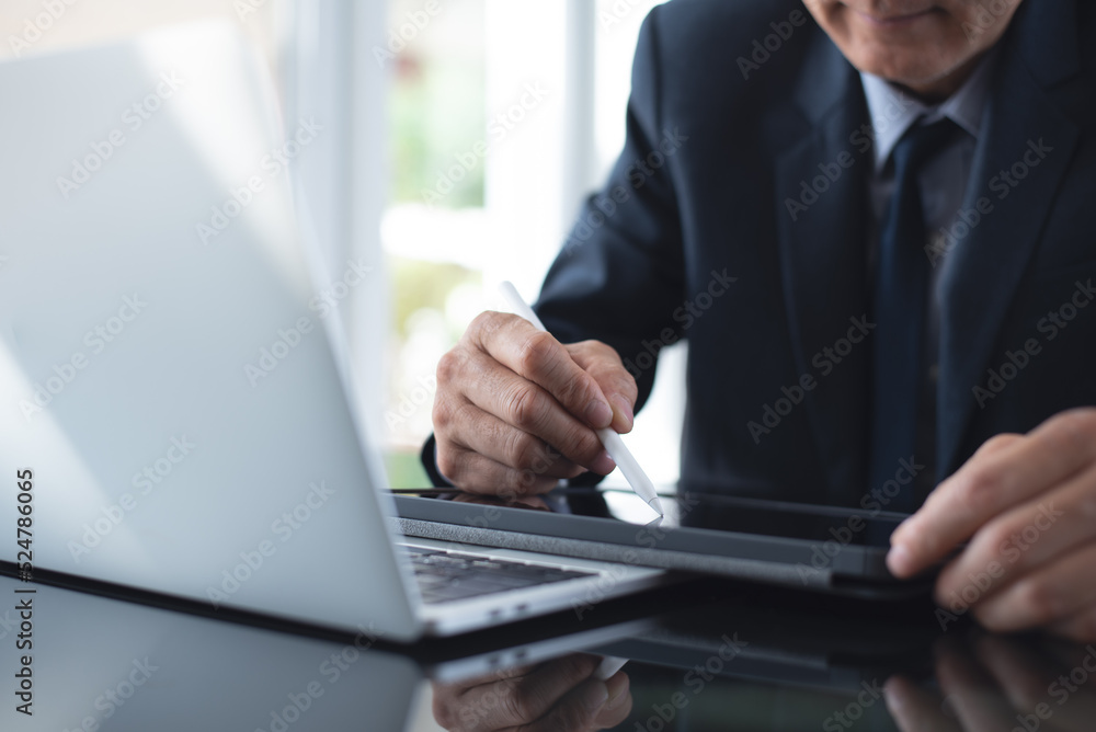 Wall mural businessman using stylus pen signing e-document on digital tablet with laptop computer on table at o