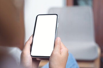 Cell phone mockup image blank white screen.  Woman hand holding, using mobile phone at home.