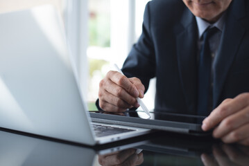 Businessman using stylus pen signing e-document on digital tablet with laptop computer on table at office, e-signing, digital document, electronic signature