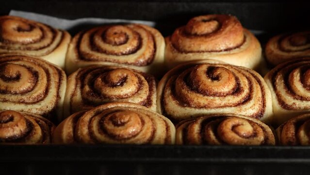 Baked cinnamon buns in the oven. Production of cinnamon rolls or Cinnabon  