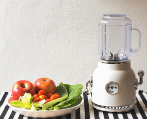 empty white vintage blender or smoothie maker  with a plate of vegetables, tomatoes and apples on ...