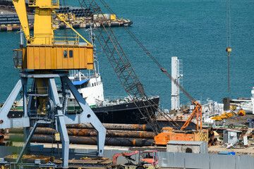 industrial seaport infrastructure, sea, cranes and raw materials, metal structures and ship, the concept of marine cargo transportation
