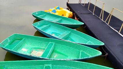Pleasure boats of green and yellow colors are standing on the pier in the rain