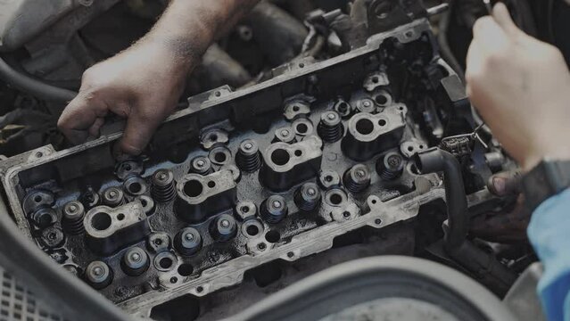 Maintenance worker fixes the car engine. installing the cylinder block head
