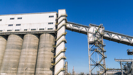Conveyor gallery at the oil refinery. Installation of coke shipment at a petrochemical plant. Silo shipment unit. Production of deep oil refining. Technological buildings at the factory.
