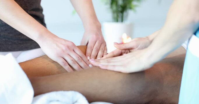 The masseur gently strokes the legs of a lying man