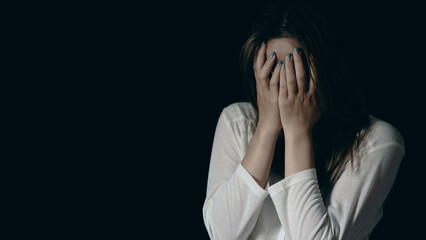 Young person woman sad, stress and loneliness sitting in dark room, Unhappy and crying teenage girl from domestic violence, An adult female expresses feelings of despair, anxiety from harassment.