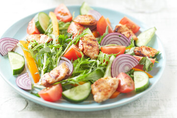 Salad with Chicken Breast, Cherry Tomatoes, Cucumber, Orange Pepper, Endive and Red Onion. Close up.	