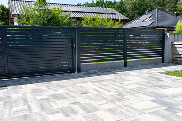 Modern panel fencing in anthracite color, visible sliding gate to the garage as well as a handle...