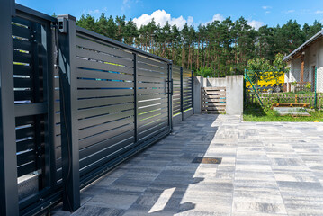 Modern panel fencing in anthracite color, visible sliding gate to the garage as well as a handle...