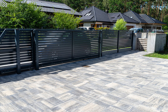 Modern panel fencing in anthracite color, visible sliding gate to the garage as well as a handle and a lock..