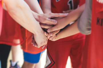Team of kids children basketball players stacking hands in the court, sports team together holding hands getting ready for the game, playing indoor basketball, team talk with coach, close up of hands
