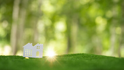 Environmentally eco-friendly real estate house. Small model building property home on grass in...