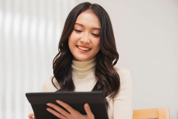 Asian girl using tablet playing game and social media or chatting with her friends.