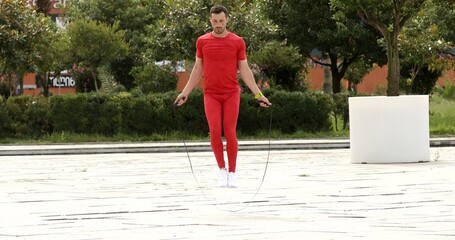 Caucasian athletic sportsman working out with jumping rope on nature.