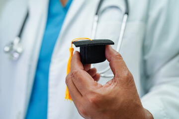 Asian woman doctor holding graduation hat in hospital, Medical education concept.