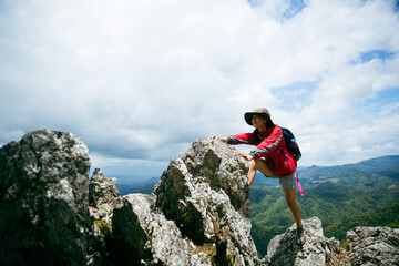 Young person hiking female climbing on top rock, Backpack woman looking at beautiful mountain...