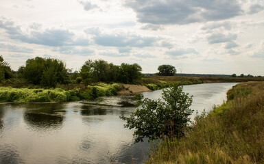 Beautiful landscape - the winding Klyazma river among the banks with green trees and a dramatic cloudy sky on a sunny day in August in the Moscow region