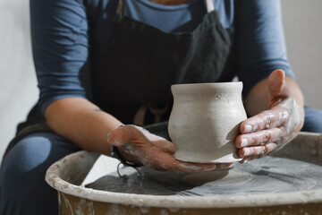 Fototapeta na wymiar Potter making bowl on wheel. self-employed pottery artist in creative studio working with raw clay shaping handmade cup or jar. Cheerful ceramics art teacher recording master class lesson in workshop