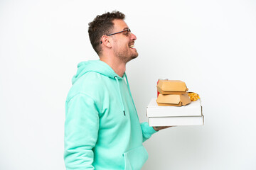 Young caucasian man holding fast food isolated on white background laughing in lateral position