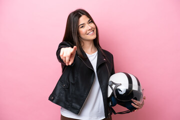 Young Brazilian woman with a motorcycle helmet isolated on pink background pointing front with happy expression
